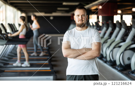 Young guy trainer in sportswear poses in middle of fitness center gym. Young guy trainer in sportswear poses in middle of fitness center gym. 121216624