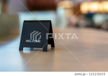 Black sign there is a message saying Welcome with a copy space is placed on a cement table for Enter the text of restaurant, store, or cafe. Black sign there is a message saying Welcome with a copy space is placed on a cement table for Enter the text of restaurant, store, or cafe. 121219315