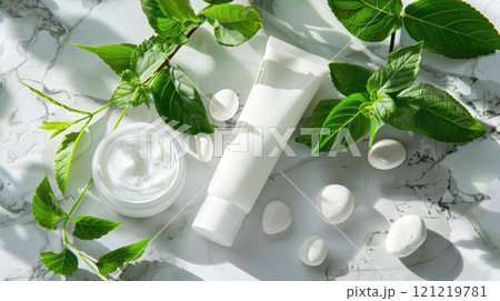 White tube of cosmetic cream on a marble surface, next to green leaves and light stones White tube of cosmetic cream on a marble surface, next to green leaves and light stones 121219781