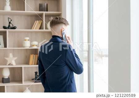 Man in a blue suit is talking on his cell phone 121220589