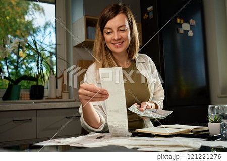 Woman holding stack of hundred dollar bills over receipts and financial bills Woman holding stack of hundred dollar bills over receipts and financial bills 121221276