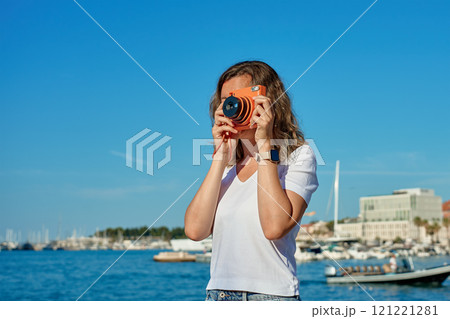 Young Woman Taking Photos in Coastal Town 121221281