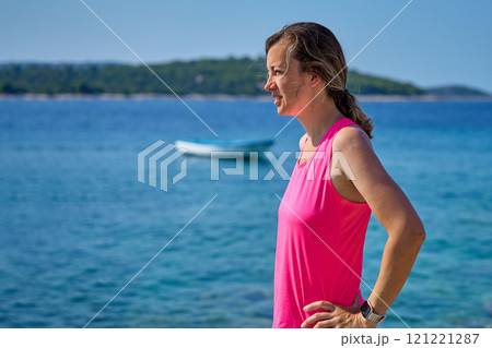 Woman resting on sea beach during fitness workout on sunny day Woman resting on sea beach during fitness workout on sunny day 121221287