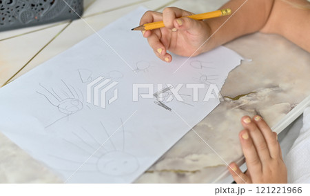 the child draws with a simple pencil on a piece of paper the child draws with a simple pencil on a piece of paper 121221966