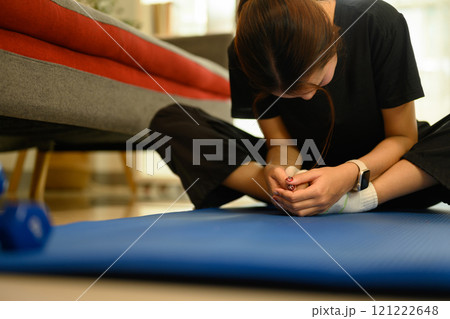 Young asian woman sitting in butterfly pose, stretching muscles on mat during home workout Young asian woman sitting in butterfly pose, stretching muscles on mat during home workout 121222648