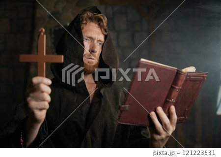 Priest holding cross and holy bible performing exorcism rite 121223531
