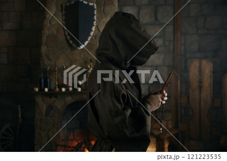 Faithful priest in robe hood praying with rosary beads and cross 121223535