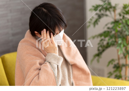 冬の部屋で頭痛に苦しむマスクをつけたミドル〜シニア女性 冬の部屋で頭痛に苦しむマスクをつけたミドル〜シニア女性 121223897