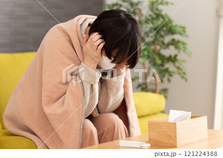 冬の部屋で頭痛に苦しむマスクをつけたミドル〜シニア女性 冬の部屋で頭痛に苦しむマスクをつけたミドル〜シニア女性 121224388