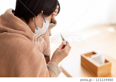 冬の部屋で頭痛に苦しむマスクをつけたミドル〜シニア女性 冬の部屋で頭痛に苦しむマスクをつけたミドル〜シニア女性 121224460