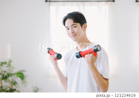 自宅でダンベルを持つ男性 自宅でダンベルを持つ男性 121224619