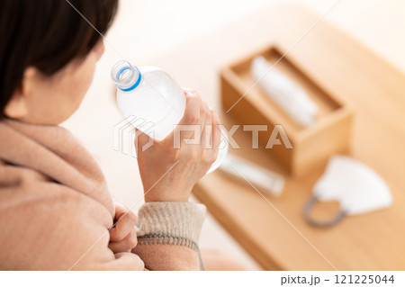 スポーツドリンクで水分補給をする風邪を引いたミドル〜シニア女性 スポーツドリンクで水分補給をする風邪を引いたミドル〜シニア女性 121225044