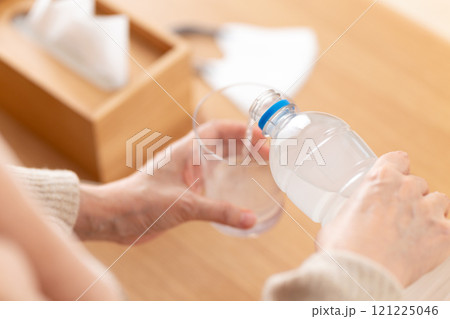 スポーツドリンクで水分補給をする風邪を引いたミドル〜シニア女性 121225046