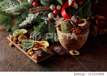 Dried fruits and nuts with Christmas wreath on a brown vintage table. Dried fruits and nuts with Christmas wreath on a brown vintage table. 121225066