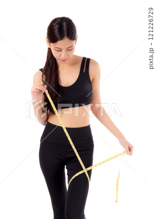 Portrait young asian woman in sportswear holding measuring tape leg for weight loss isolated. 121226729