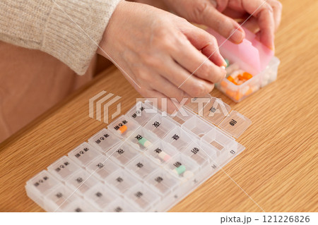 ピルケースに常用薬を入れるミドル〜シニア女性の手元 121226826