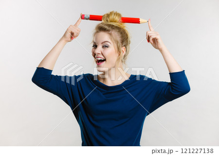 Happy blonde woman having big pencil in hair 121227138