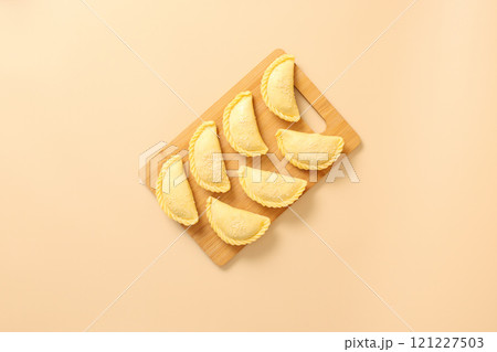 Top view on wooden board with raw pies, frozen semi-finished products bakery. 121227503