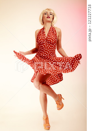 Pinup girl in blond wig retro dress dancing Pinup girl in blond wig retro dress dancing 121227718