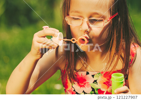 Little girl child blowing soap bubbles outdoor. 121227907