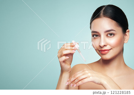 Young beautiful woman applying face serum 121228185