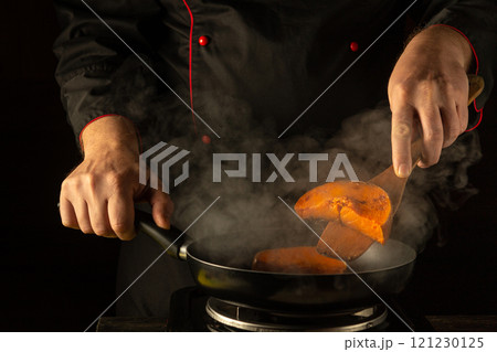 In a warmly lit kitchen, a chef expertly flips slices of bright orange pumpkin in a sizzling pan. Steam rises, heightening the culinary atmosphere In a warmly lit kitchen, a chef expertly flips slices of bright orange pumpkin in a sizzling pan. Steam rises, heightening the culinary atmosphere 121230125