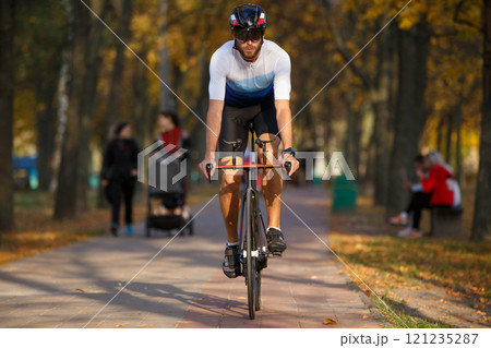 Cyclist rides through a park adorned with autumn leaves on a sunny day Cyclist rides through a park adorned with autumn leaves on a sunny day 121235287