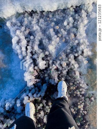women's feet in white shoes are standing on an interestingly shaped ice women's feet in white shoes are standing on an interestingly shaped ice 121235683