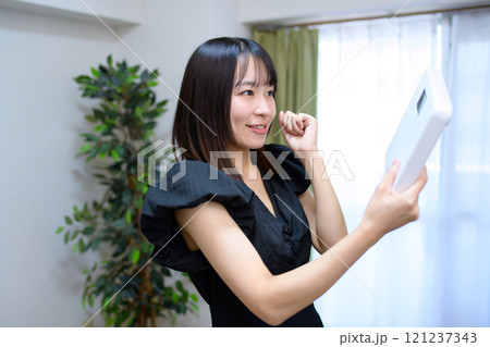 体重計を持って喜ぶ女性　ガッツポーズ　体重を気にする　ダイエット　成功 121237343