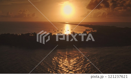 Golden sunrise illuminate yachts anchored near tropical island with lush vegetation in Rangiroa, French Polynesia, breathtaking sky seascape. Remote wild nature paradise, exotic summer travel. Aerial Golden sunrise illuminate yachts anchored near tropical island with lush vegetation in Rangiroa, French Polynesia, breathtaking sky seascape. Remote wild nature paradise, exotic summer travel. Aerial 121237621