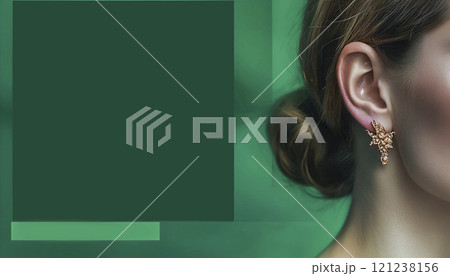 Close-up of a woman on an emerald background with an accent on an earring with a gemstone. 121238156