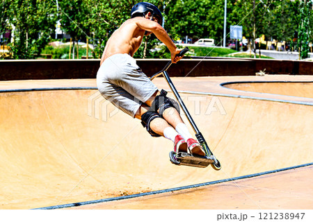 Young man practicing Scootering (Freestyle Scootering) in the new SkatePark of the central park of Igualada, Barcelona, Spain 121238947