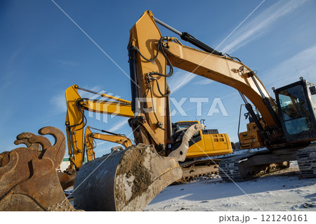 Multiple excavators operating on a construction site in winter conditions. Multiple excavators operating on a construction site in winter conditions. 121240161