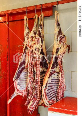 Dried pig carcasses cut in half hang on the hooks in a butcher shop Dried pig carcasses cut in half hang on the hooks in a butcher shop 121240831