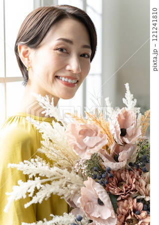 屋内で花束を持つミドル女性 屋内で花束を持つミドル女性 121241810