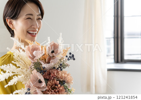 屋内で花束を持つミドル女性 121241854