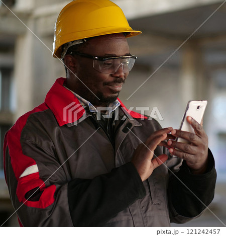 African american workman with smartphone at construction site 121242457