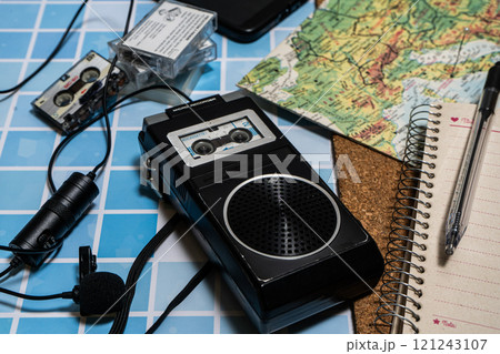 Old micro cassette recorder with its mic and several cassettes next to a map. Old micro cassette recorder with its mic and several cassettes next to a map. 121243107