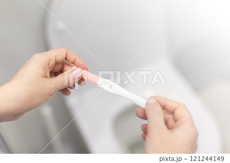 Holding positive pregnancy test in rest room 121244149