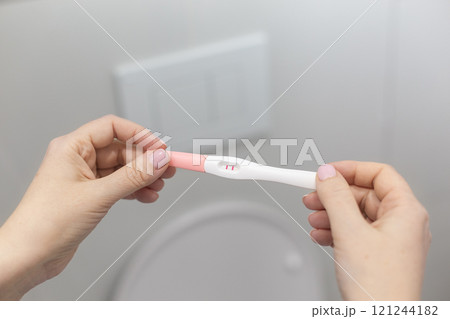 Holding positive pregnancy test in rest room 121244182
