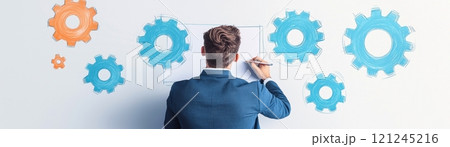 A professional man is drawing colorful gears on a wall, innovation and strategic planning. 121245216