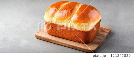 A freshly baked loaf of bread resting on a wooden cutting board 121245829