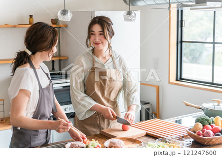 料理教室・クッキングスクールで料理を教える講師の女性と生徒の女性 121247600