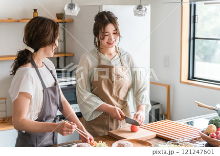 料理教室・クッキングスクールで料理を教える講師の女性と生徒の女性 121247601