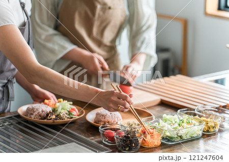 料理教室・クッキングスクールで料理を教える講師の女性と生徒の女性 121247604