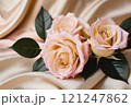 ゴールドのシルクの布の上に置かれたパステルピンクのばら 121247862