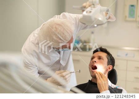 Elderly male dentist examining male patient Elderly male dentist examining male patient 121248345