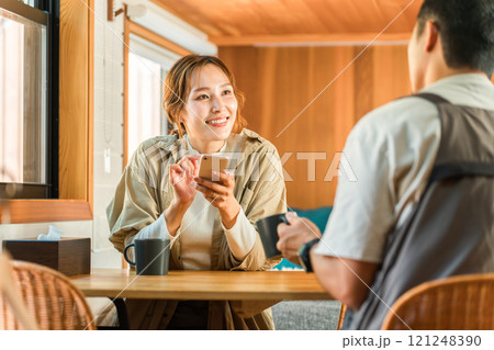 コテージ・キャビン・ログハウスでコーヒーを飲みながら笑顔で会話する夫婦 121248390