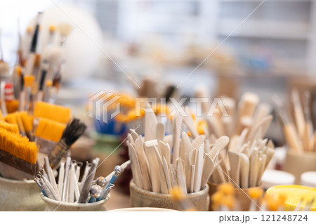Variety of brushes, wooden spatulas, scrapers used in manual production of ceramic products. 121248724