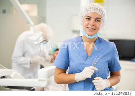 Young woman nurse in blue suit is standing in dental office, clinic Young woman nurse in blue suit is standing in dental office, clinic 121248837